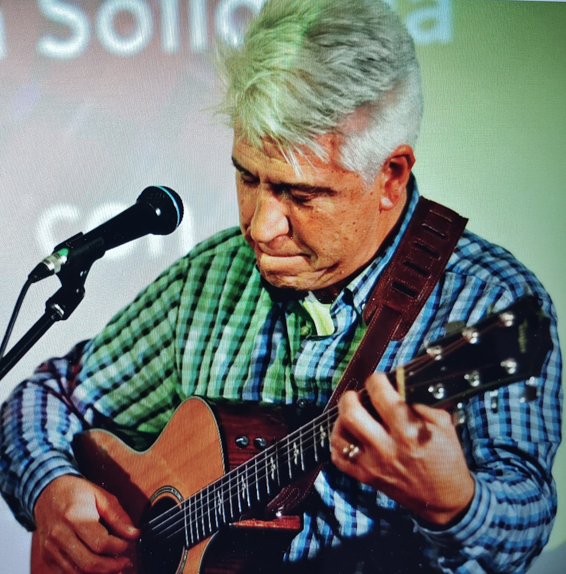 Joan Marc concentrado, pulsando los acordes de la guitarra acústica junto al micrófono.