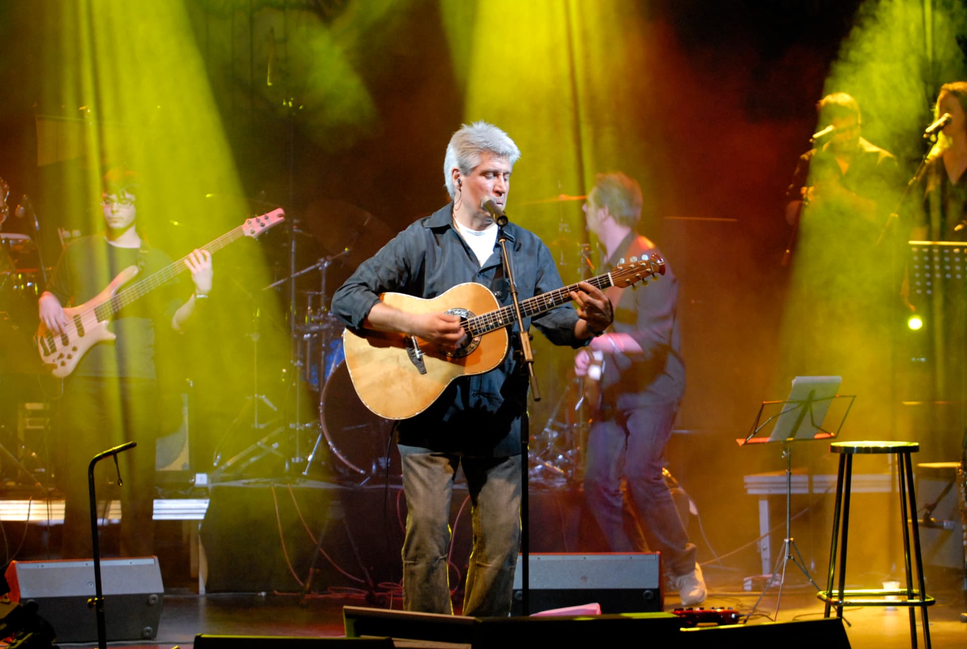 Joan Marc cantando y tocando ante su banda, con focos amarillos y humo sobre el escenario.