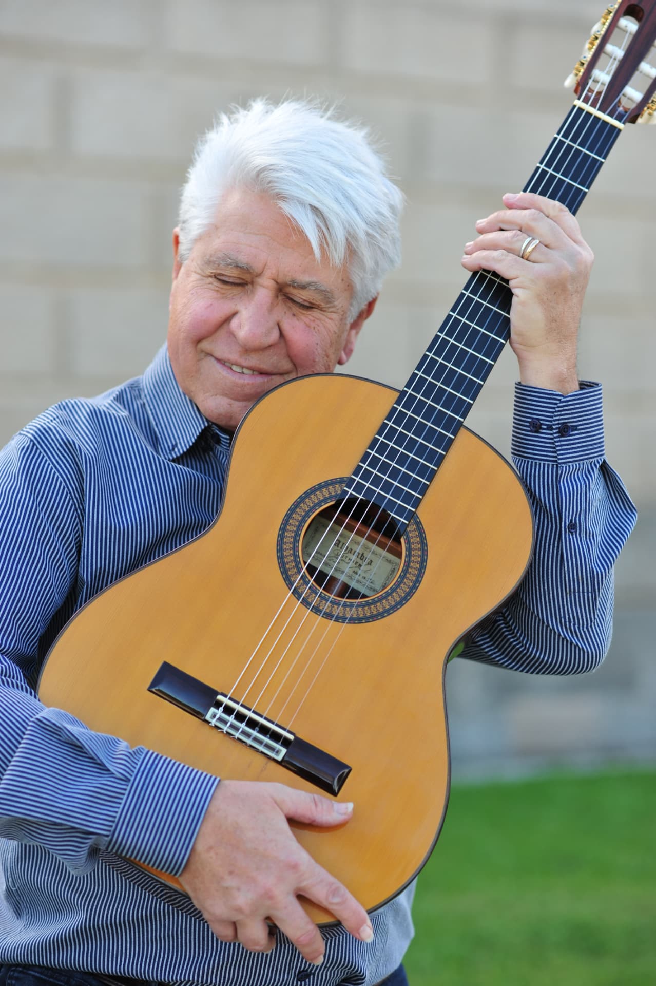 Joan Marc, con los ojos cerrados y una sonrisa, apoya la mejilla en la guitarra clásica mientras la abraza con ambas manos.