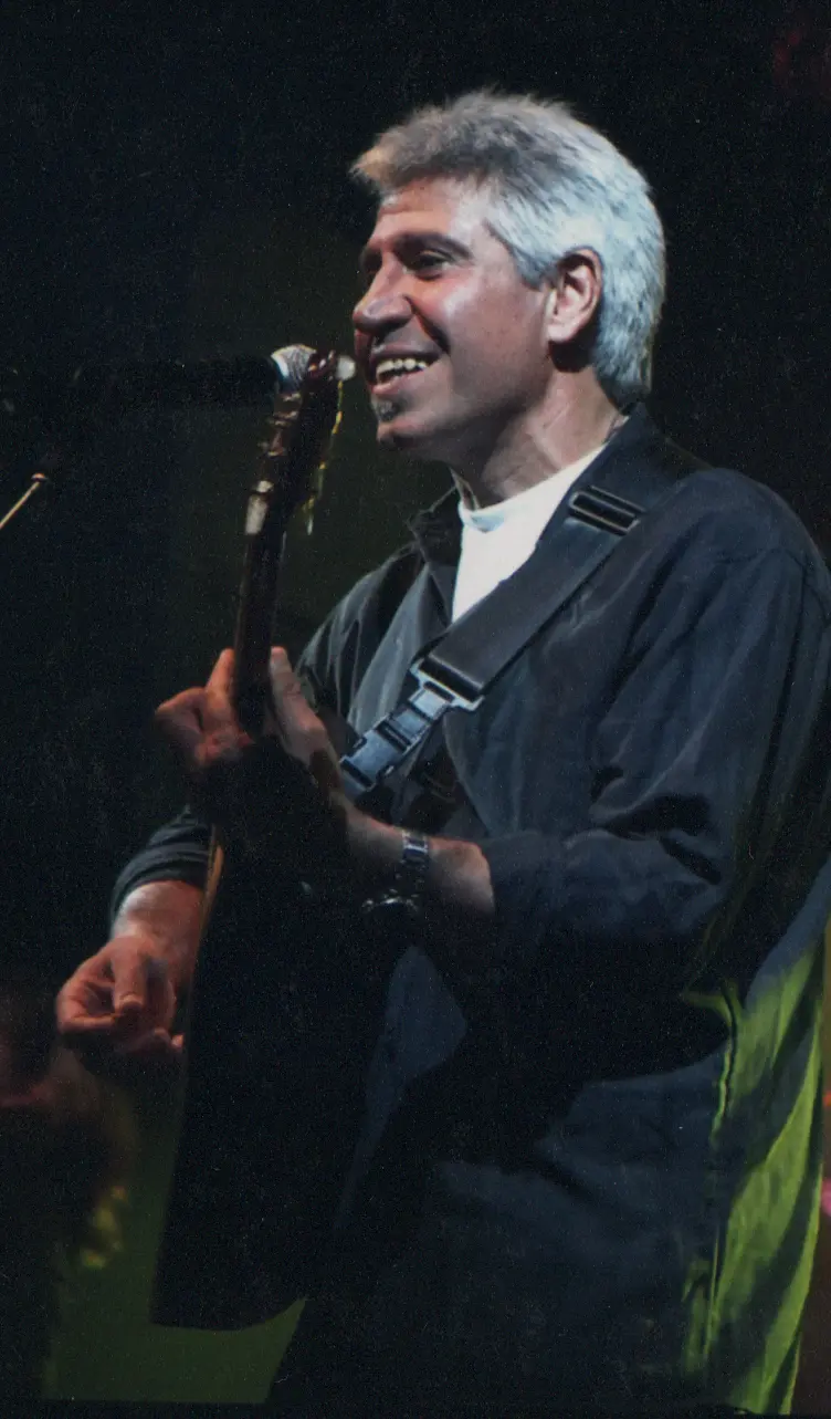 Joan Marc de perfil, cantando y tocando la guitarra bajo una luz de recorte verdosa.