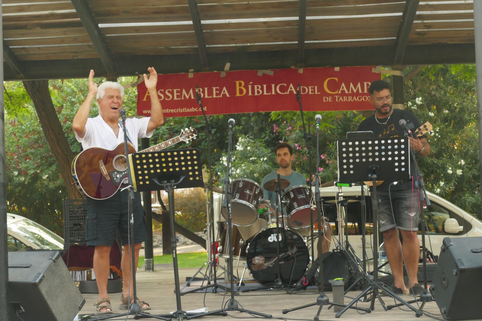 Plano general del escenario: Joan Marc, con la guitarra al hombro y las manos levantadas, canta junto al baterista y un bajista.