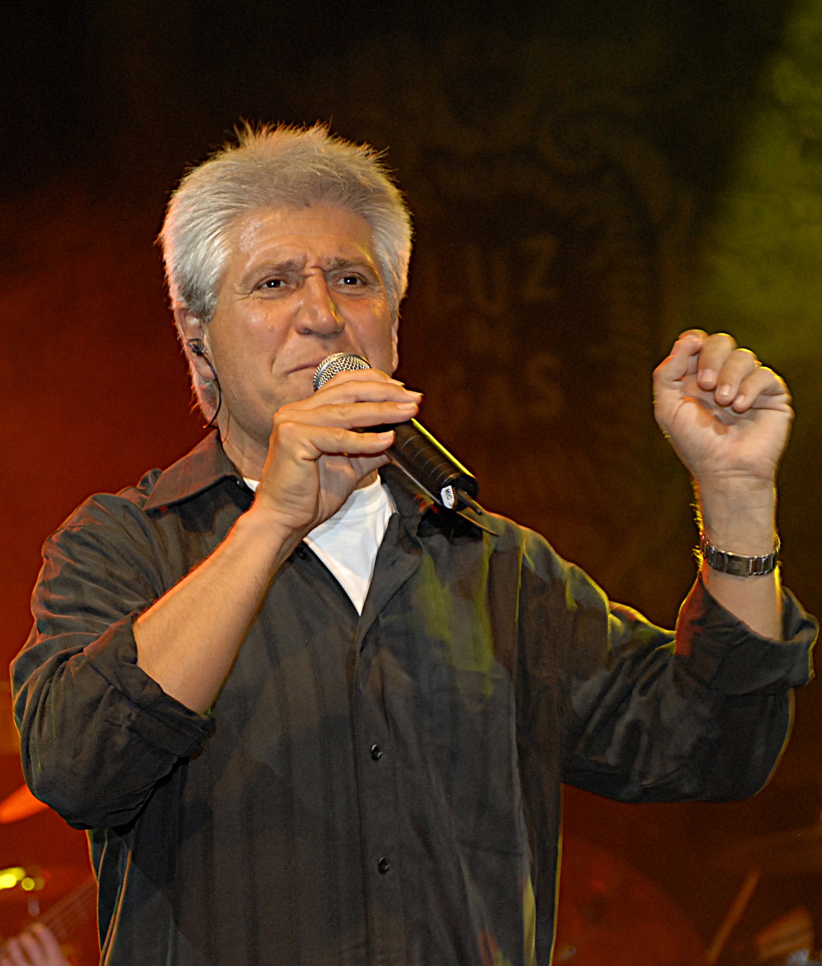 Joan Marc cantando con el micrófono y la mano levantada, con el rótulo de la sala al fondo.