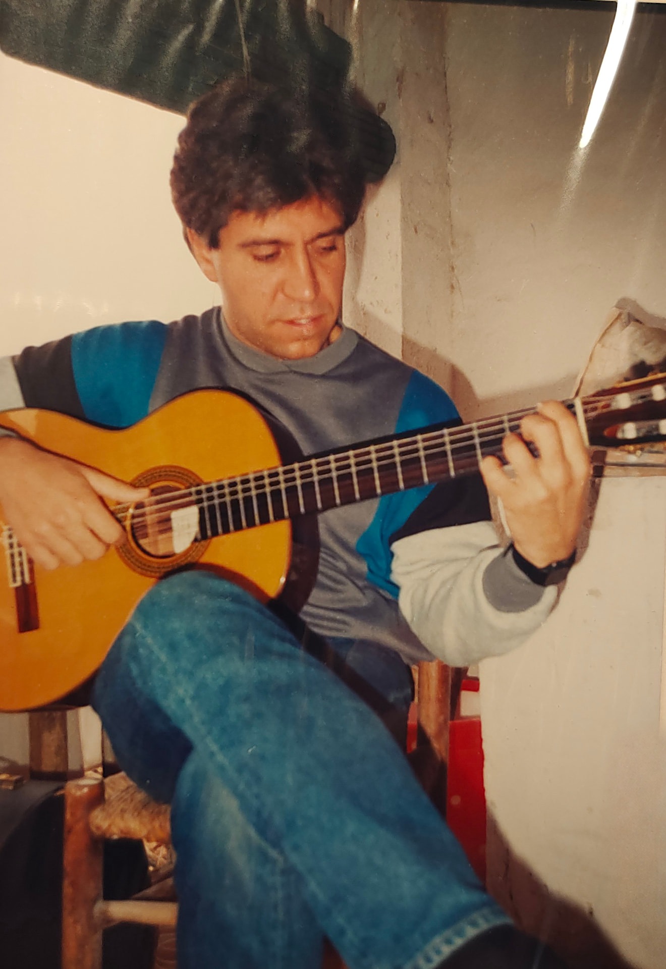 Joan Marc sentado con las piernas cruzadas, mirando las cuerdas mientras toca la guitarra clásica.