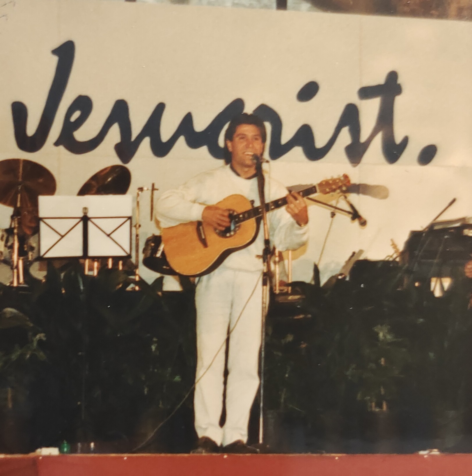 Joan Marc de pie con la guitarra ante un telón con la palabra «Jesucrist».